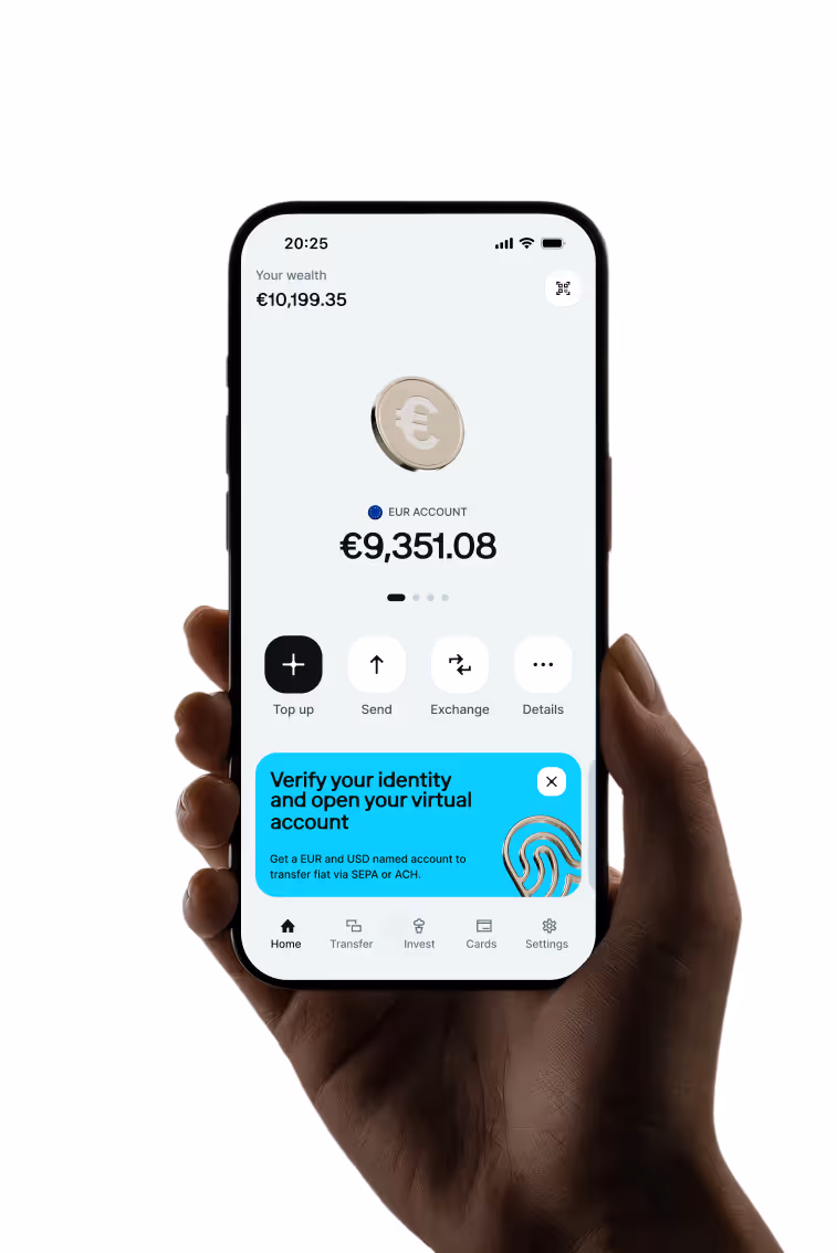Hand holding a smartphone showing a banking app with a EUR account balance of €9,351.08 and a wealth total of €10,199.35, featuring options to top up, send, exchange, and view details, plus a blue notification to verify identity and open a virtual account.
